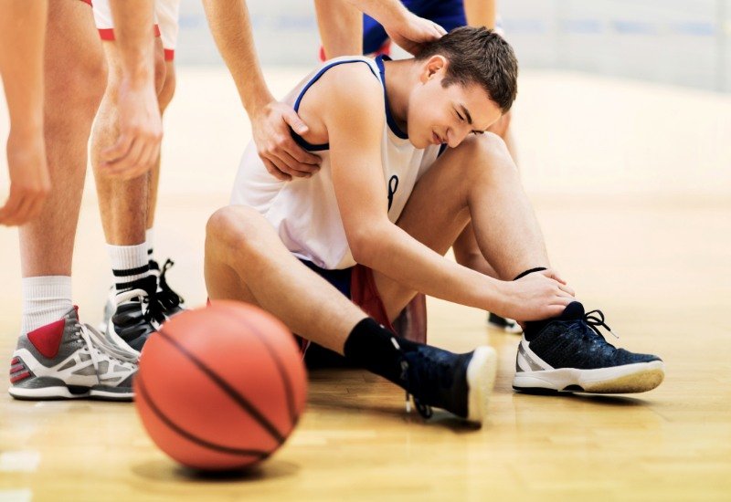 Chico joven entrenando al baloncesto en Zaragoza y doloriido con lesiones musculares
